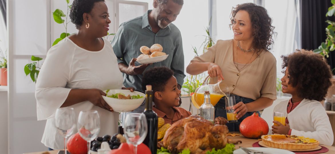 African american grandparents holding food near family and thanksgiving dinner