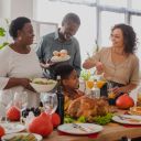 African american grandparents holding food near family and thanksgiving dinner